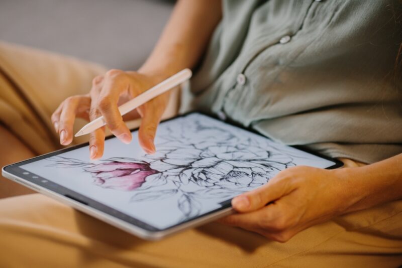 Osoba crta digitalnu ilustraciju na tabletu pomoću olovke, prikaz savremene digitalne umetnosti i NFT kreativnosti