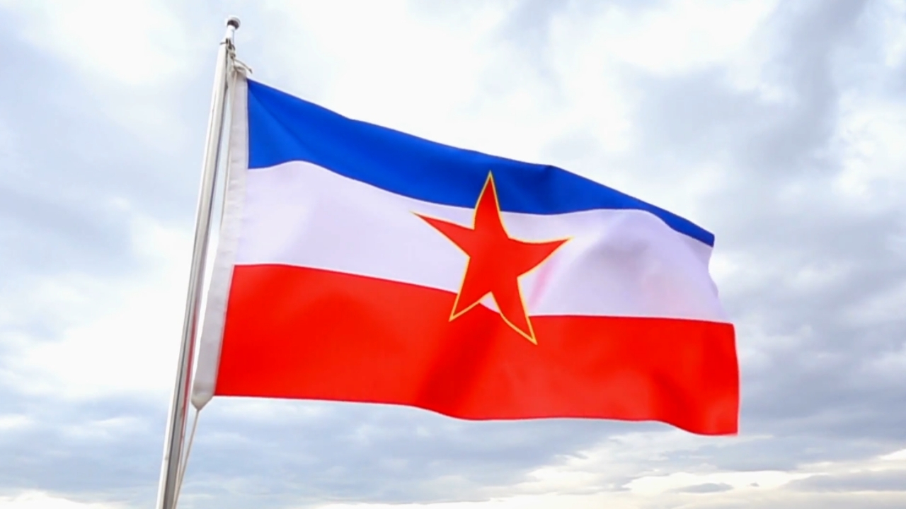 Zastava Socijalističke Federativne Republike Jugoslavije na jarbolu pod oblačnim nebom